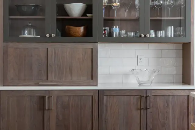 Builder partnership kitchen in Norwell, MA with walnut base cabinets, glass-front gray uppers and white subway tile