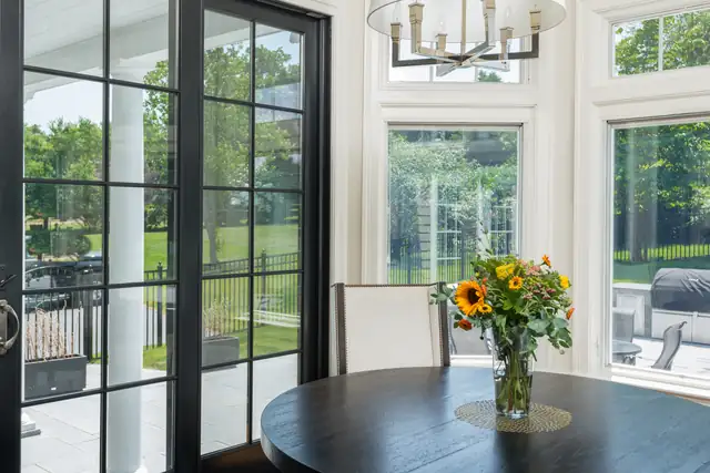 Greater Boston home addition with black-framed glass doors, a round dining table and bright windows