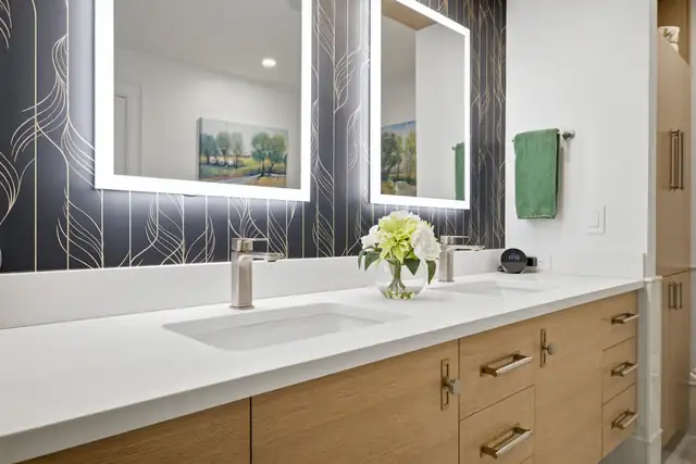 Braintree, MA primary bath with a rift sawn white oak floating vanity, Arctic White quartz and LED mirrors