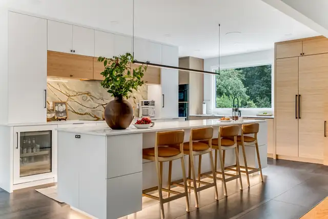 Marshfield, MA first floor remodel with a white quartz island, leather counter stools, white oak pantry cabinets and a linear pendant